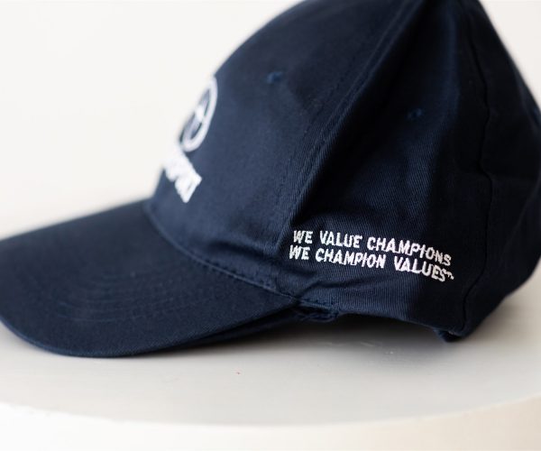 Blue TrueSport branded ball cap with side embroidery reading "WE VALUE CHAMPIONS, WE CHAMPION VALUES."