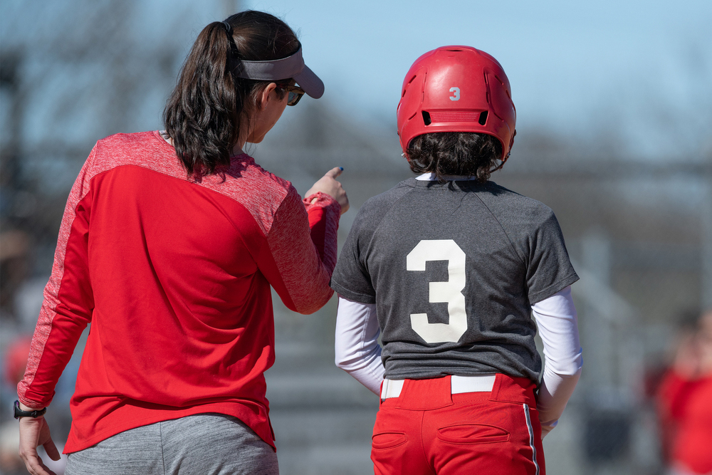 Female softball coach talking to player.