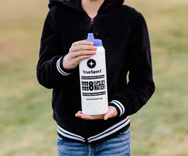 Young girl holding a white TrueSport branded water bottle.